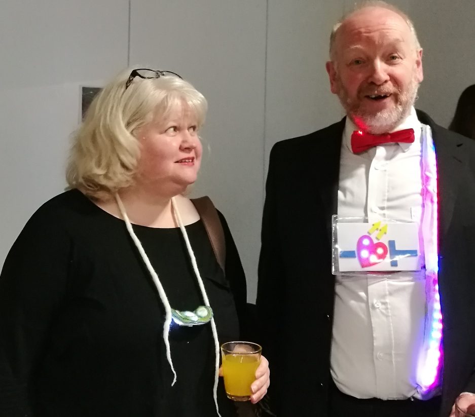 Caroline Kelly wearing her necklace made with handmade felt, slices of stalactite and LEDs next to Richard Millwood wearing his LED lit bowtie, braces and beating 'LED by the heart' decoration