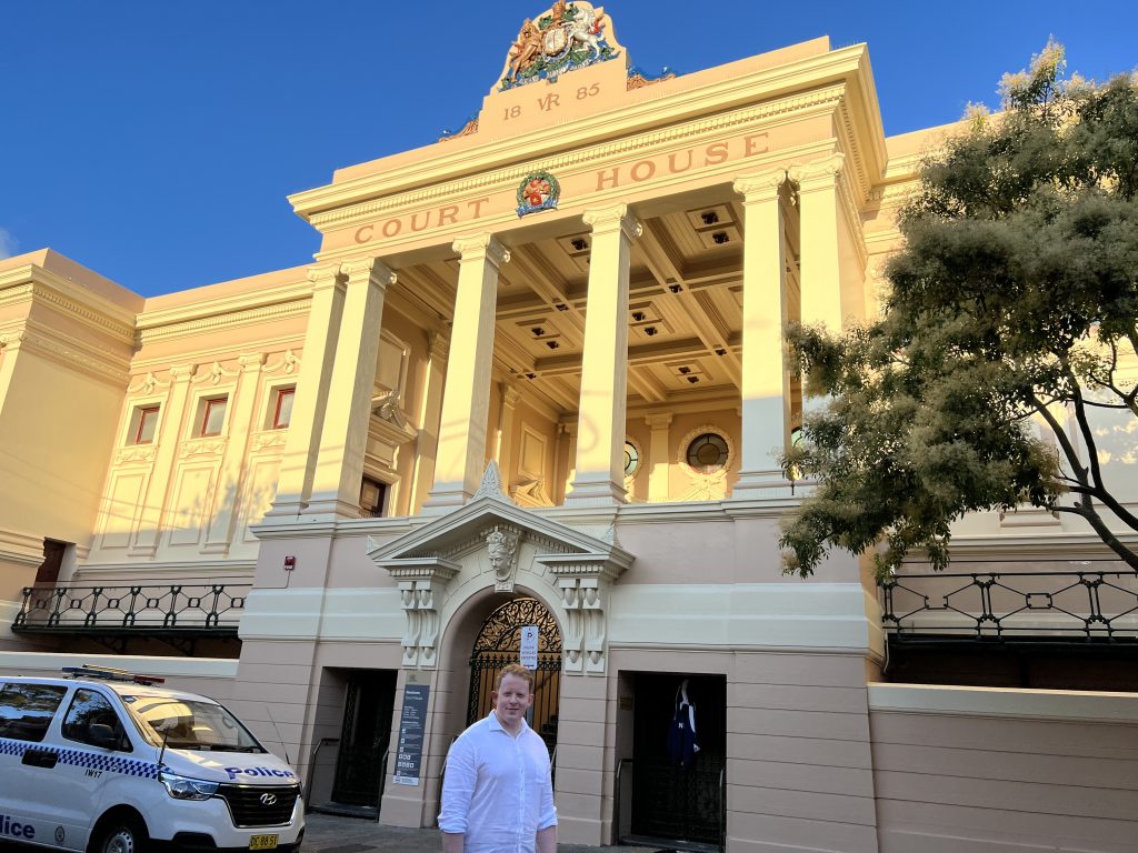 The grand pillared Courthouse building in Newtown Sydney catching the setting sun's orange light with Patrick standing in the foreground.