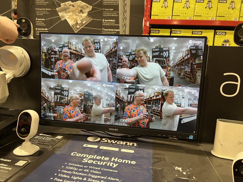 A video screen with four images from four security cameras in a hardware store. Patrick and me feature different angles in each image.