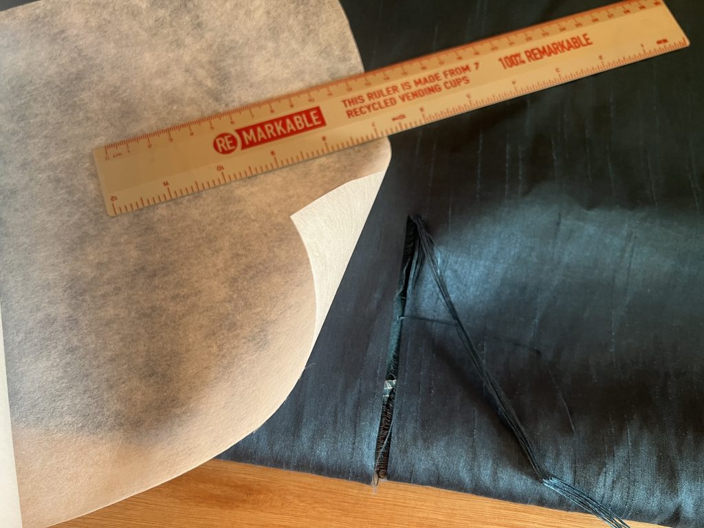 A torn curtain with embroidery stabilising material and ruler.