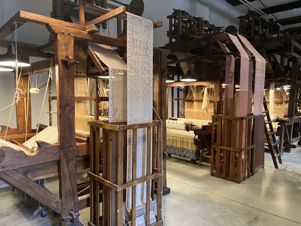 An array of Jacquard looms, with punched card programs defining the weave.