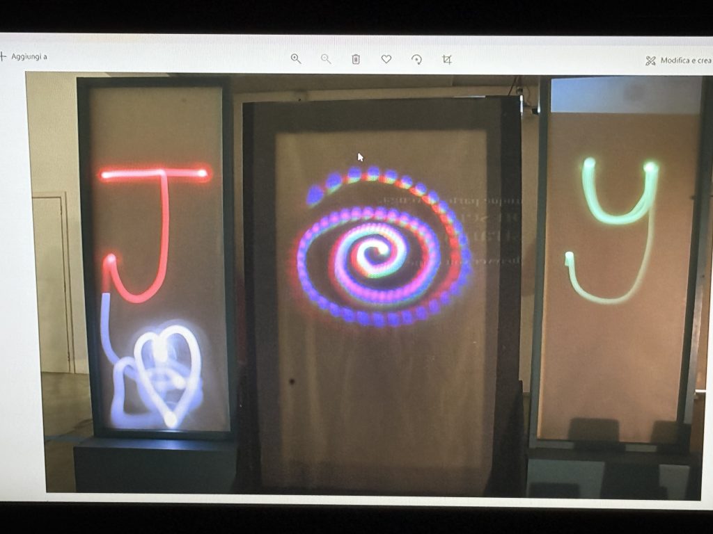 The letters j (in red), o (in white and purple) and y (in green) painted with torches using a slow-shutter time-lapse photograph.